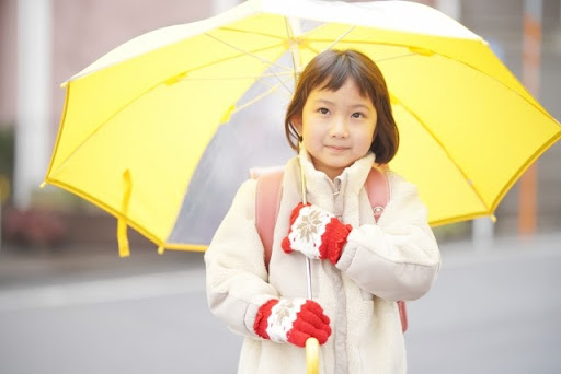 黄色い傘をさす小学生の女の子