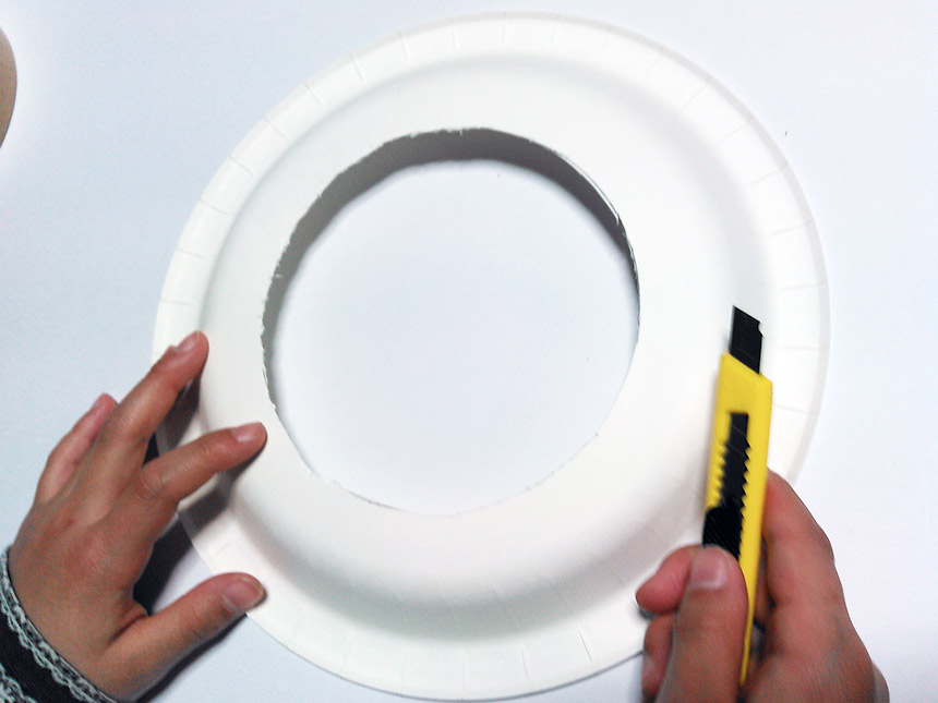 紙皿に描いた円をカッターで切り抜く