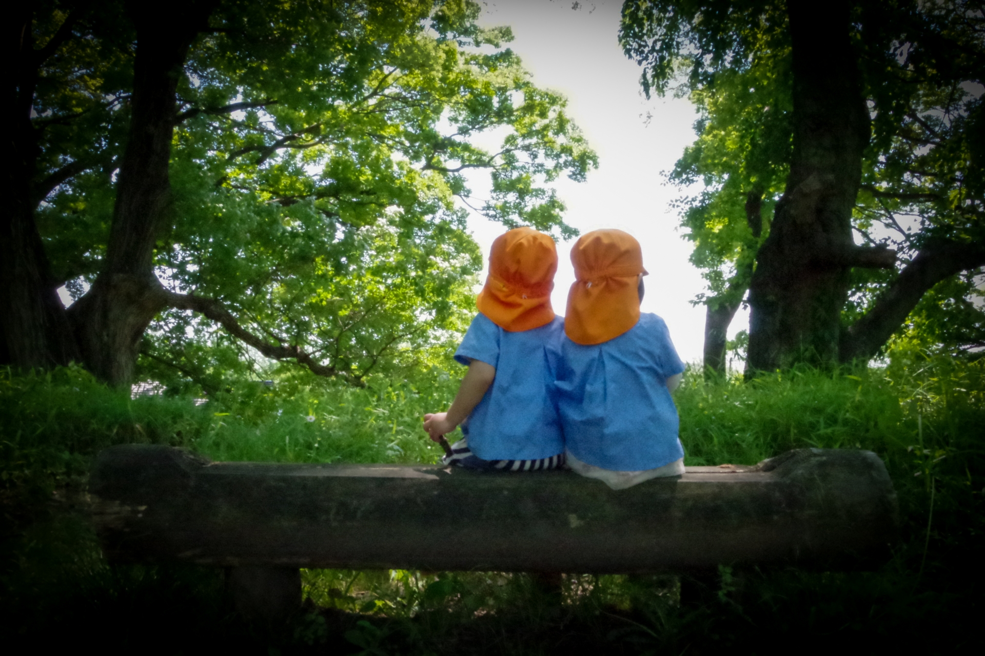 木陰でベンチに座る男の子と女の子