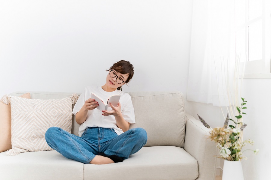 ソファで本を読んでいる女性の写真