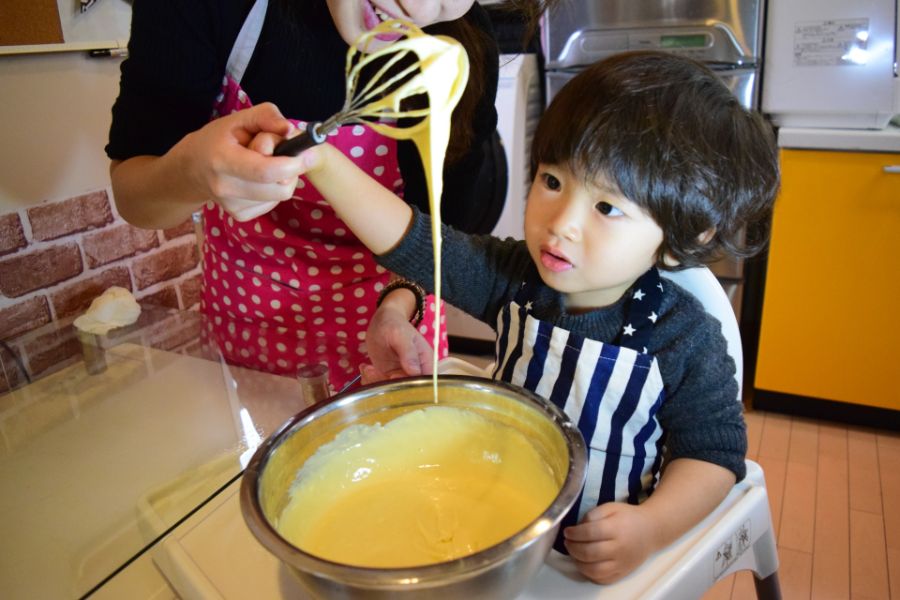 親子が泡立て器をもってお菓子作りをしている写真