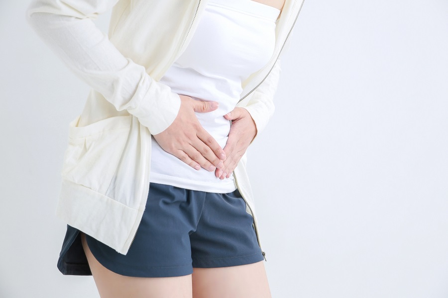 お腹を押さえる女性の写真