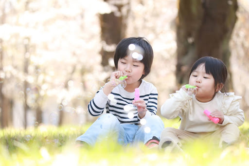 桜の下でシャボン玉を拭く子供達